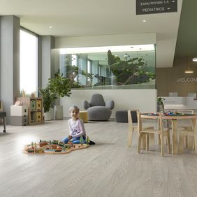 Oak effect flooring laid in a hospital waiting area with a child playing with toys