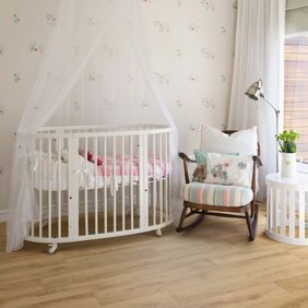 Light oak wood effect flooring in a nursery with white cot and rocking chair 