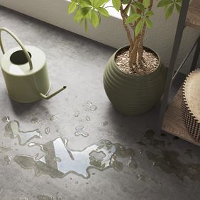 Upclose image of water spilled from a watering can onto grey flooring