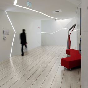 White oak wood effect flooring in a quirky corridor with red seat and strip lighting 