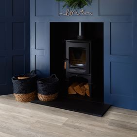 Oak effect flooring in a room with dark blue coloured walls and a log burning fire