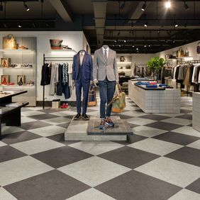 Retail shop with clothes display featuring a dark grey and light grey checker board laid flooring 