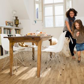 Light oak wood effect flooring in a family dining room with rustic table and white chairs