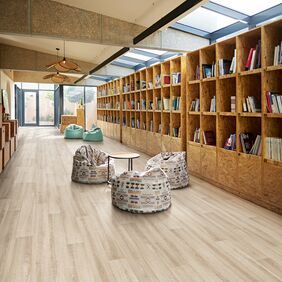Ash effect flooring straight laid in a modern library with beanbags and wooden bookshelves