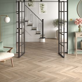Oak effect flooring laid in a herringbone style in a front room leading to the hallway