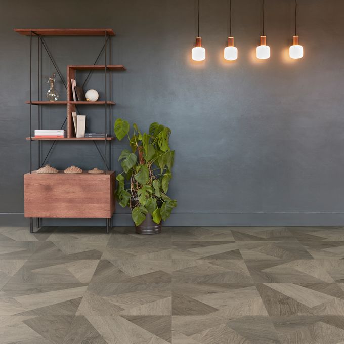 Oak effect flooring in a prisma style laid in a room with dark grey wall and a shelving unit