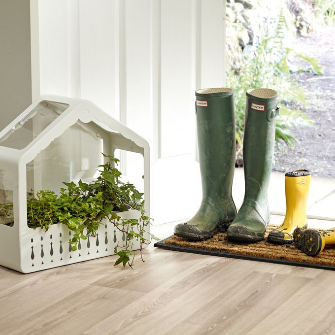 Light oak effect wood flooring in a back door area with a dirt mat and wellington boots 