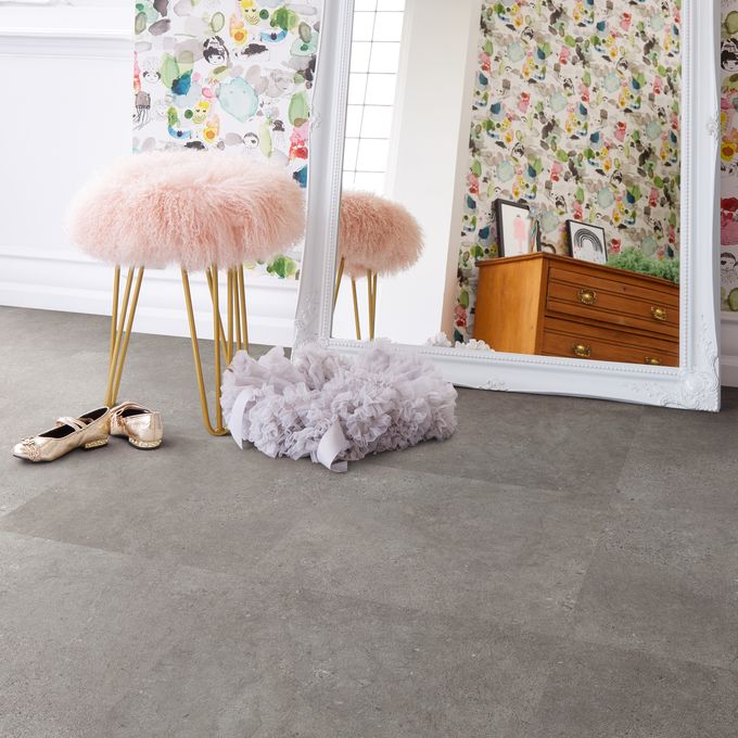 Mirror propped up against the wall with pink fluffy stool and concrete effect flooring