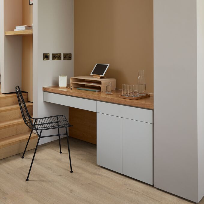 Oak effect flooring laid in a home office with white cupboards and wooden top