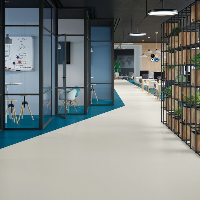 Light coloured flooring laid in an office setting with dark blue sections for privacy 
