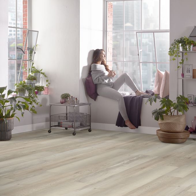 Woman sat on the window seatingwith pink accessories featuring light oak wood effect flooring