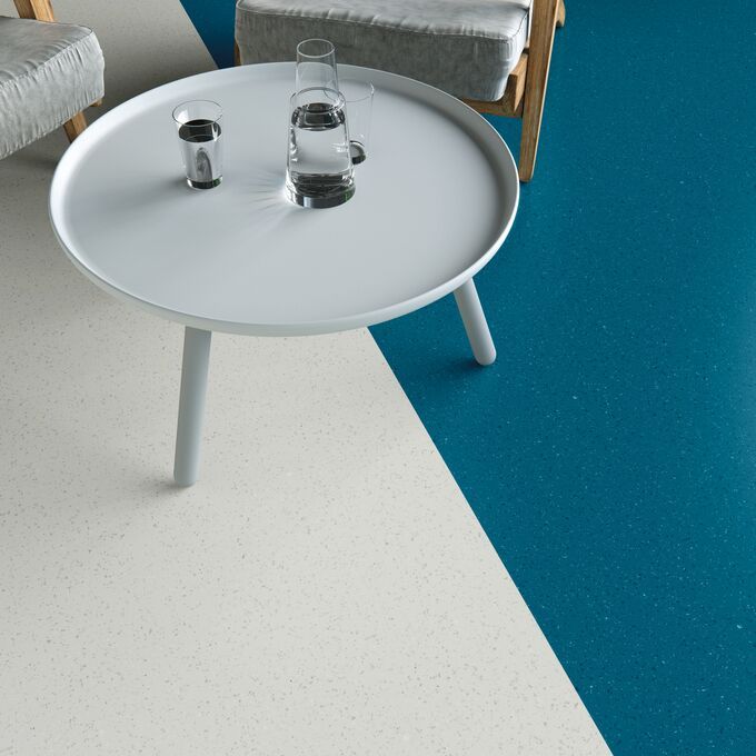 Blue and white coloured flooring with a white table and grey chairs
