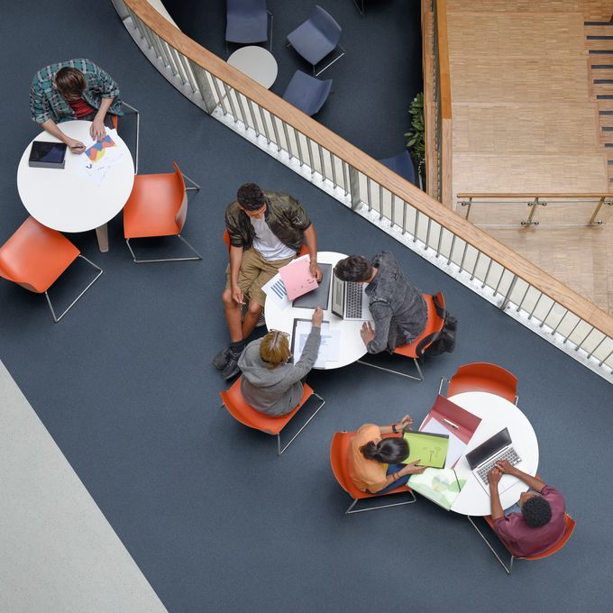 Dark blue safety flooring in a break out area with seating and tables