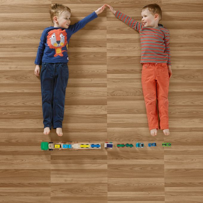 Two boys playing lay down playing with trains featuring ash wood effect flooring 