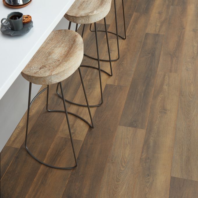 Close up of dark oak wood effect flooring with stools around a breakfast bar