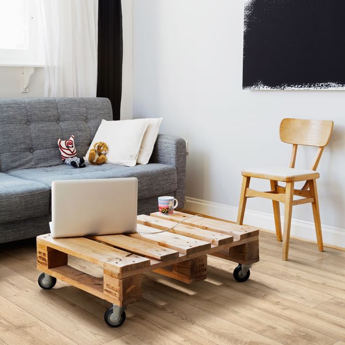 Light oak wood effect flooring in a living room with blue sofa and a rustic coffee table 