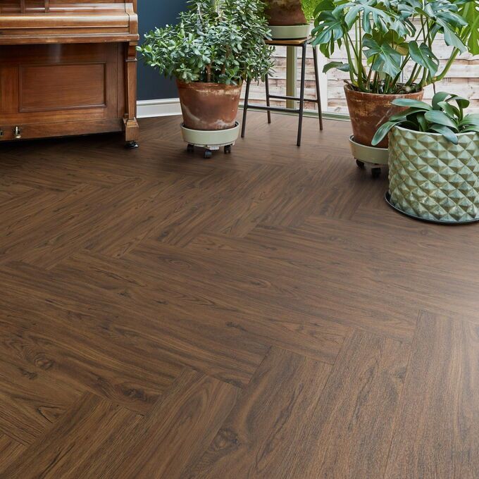 TLC Original in Walnut laid next to a piano and various potted plants