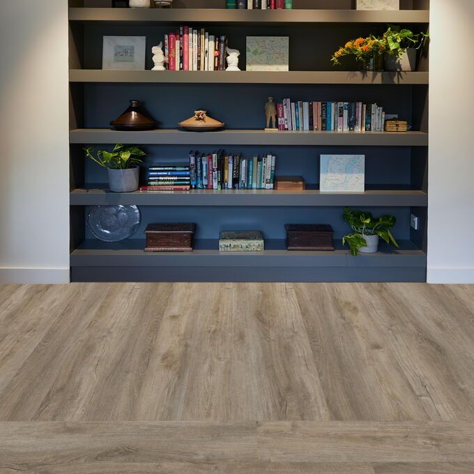 TLC Original in Courtyard Oak laid in front of a book/ornament shelf