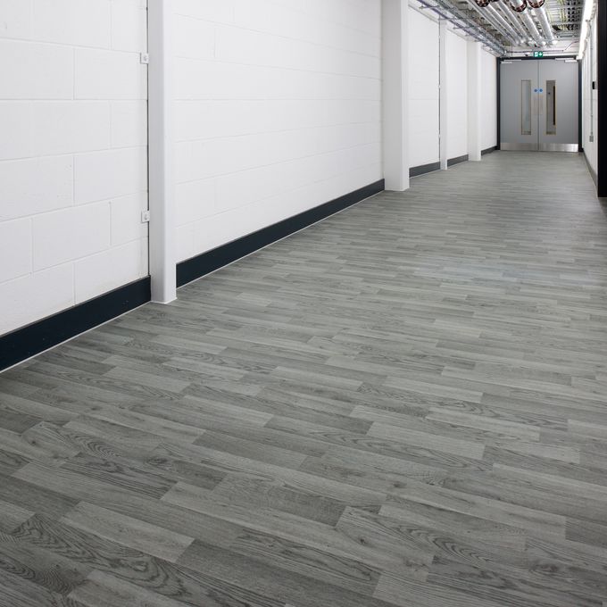 Silver grey oak wood effect flooring in a university corridor with white walls and grey door
