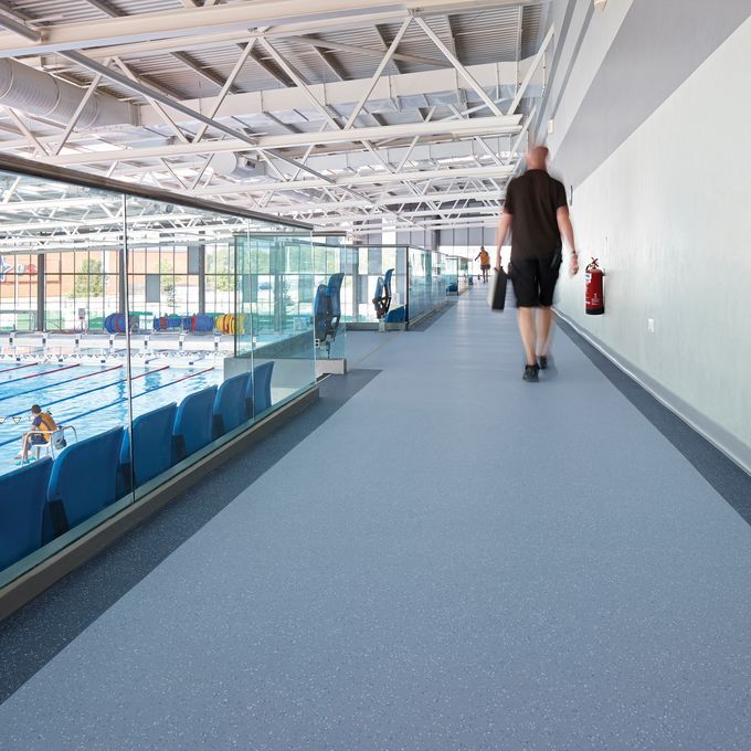 Blue safety flooring in a public swimming bath with seating area and walkway