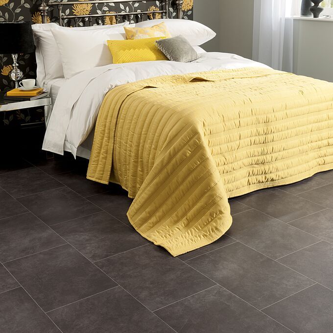 Black slate effect flooring in a bedroom with yellow bedding