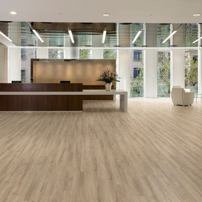 Large modern reception area with glass windows white seats and oak plank pattern flooring