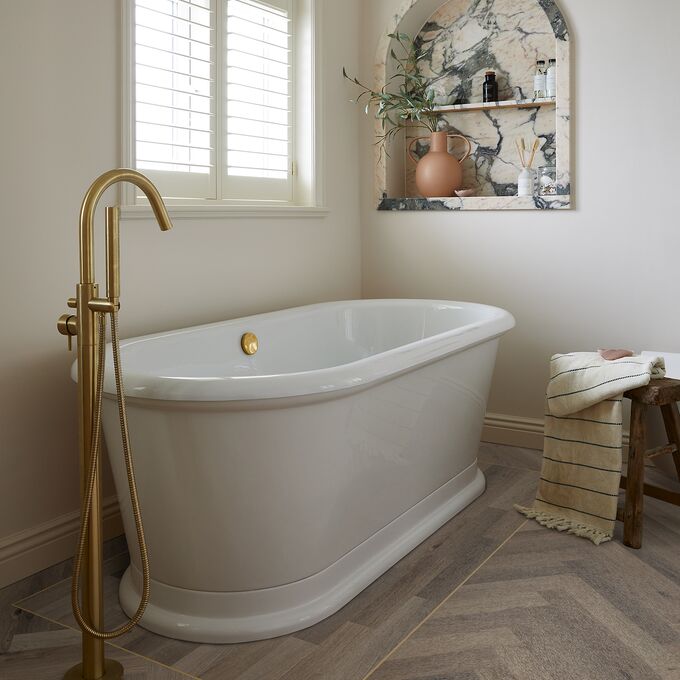Oak effect flooring laid in a large parquet style in a bathroom with a freestanding bath
