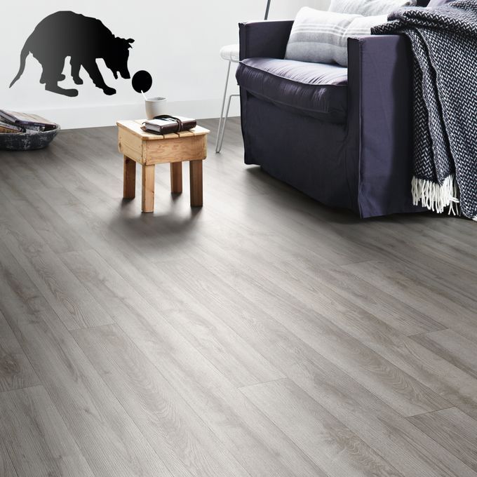 Grey oak wood effect flooring in a living room with dark blue chair and small rustic table 