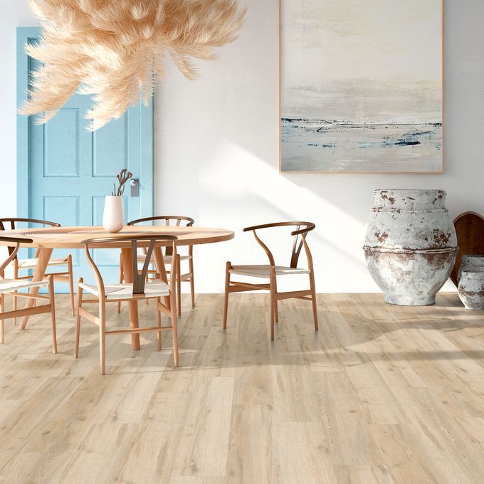 Light oak effect flooring in a room with a small wood dining table and chairs
