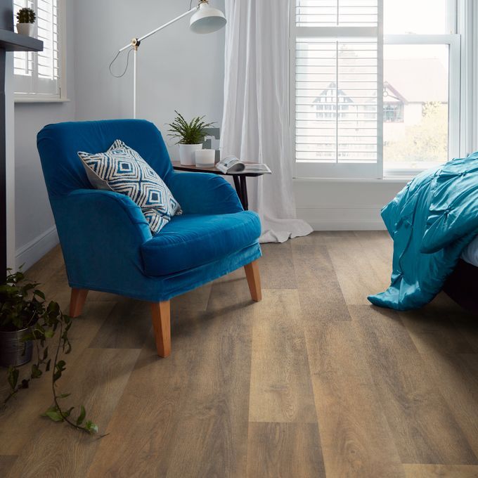 Dark oak wood effect flooring with a Blue velvet armchair and floor lamp 