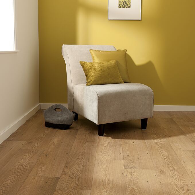 Oak effect flooring laid in a room with yellow walls and a cream arm chair