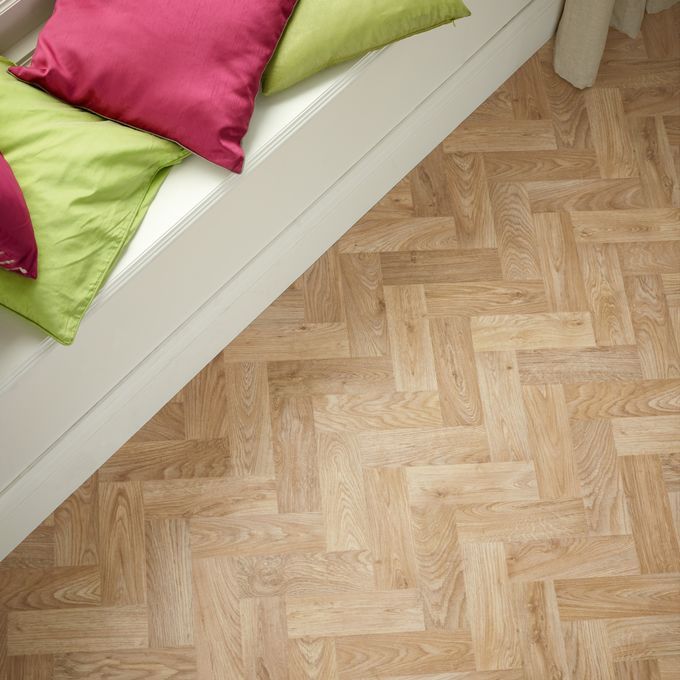 Close up of light wood effect flooring in a parquet design near a window seating area