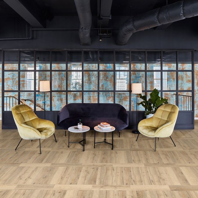 Oak effect flooring laid in a trendy waiting area with blue and yellow velvet chairs