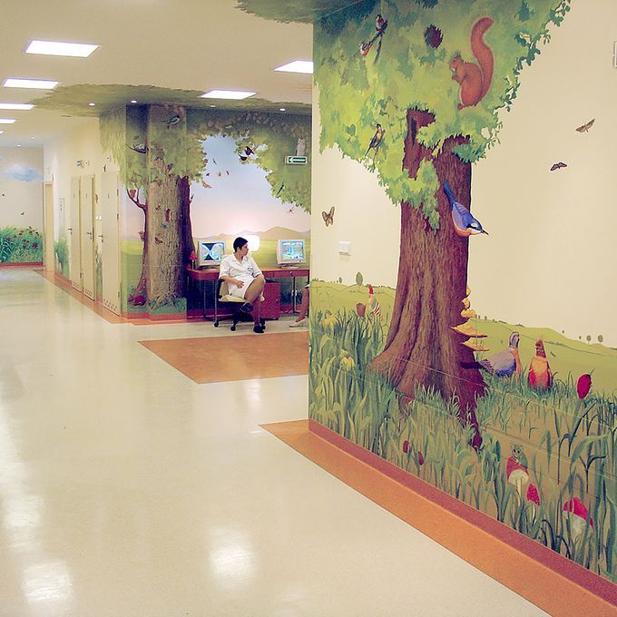 Children's hospital ward with light coloured flooring and woodland mural on the wall