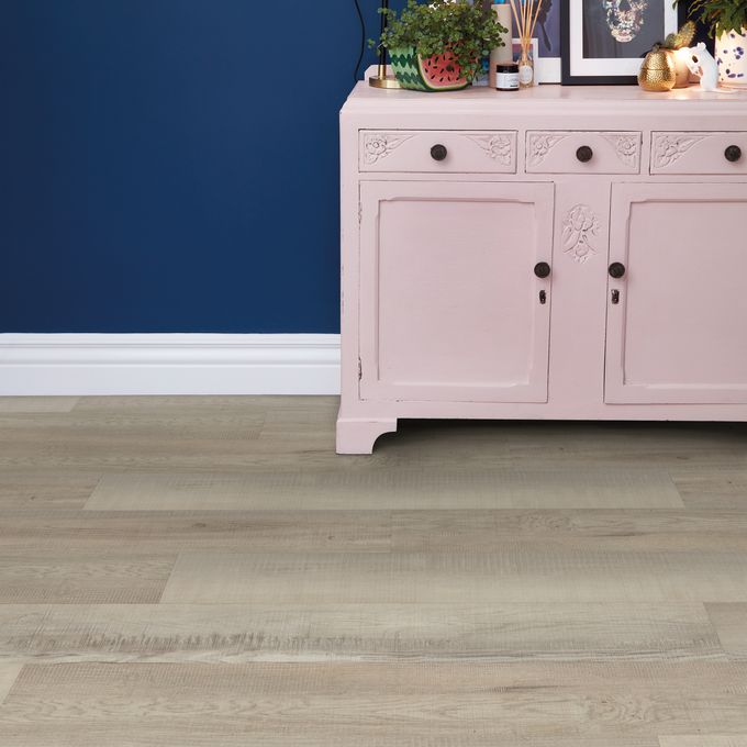 Light wood effect flooring with a baby pink dresser 