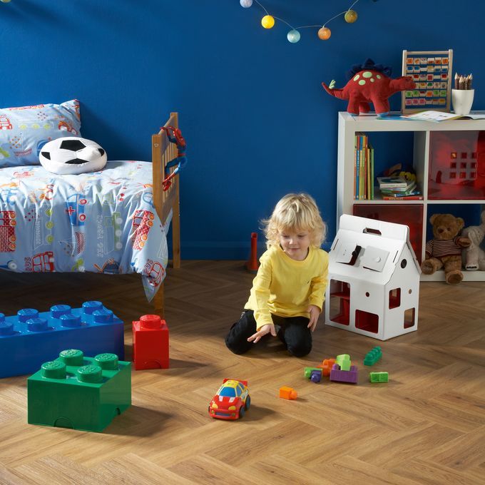 Little boy plating with lego and cars with brown wood effect flooring laid in a Herringbone pattern 