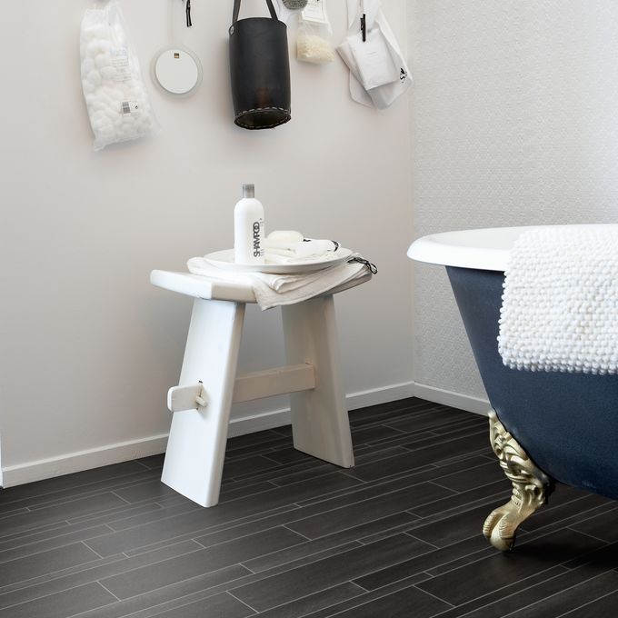 Black slate effect flooring in a bathroom with a freestanding bath with gold feet 