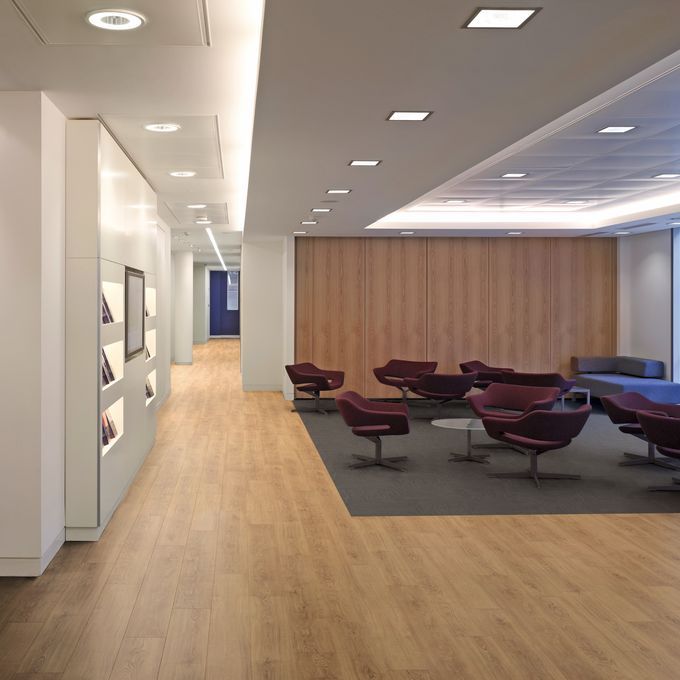 light oak effect flooring and Rich oak effect flooring used to create zonal space waiting area with small table and lounge chairs