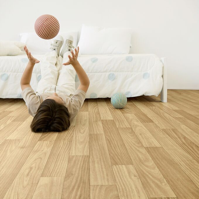 Oak effect flooring in a bedroom with a person laid down playing ball