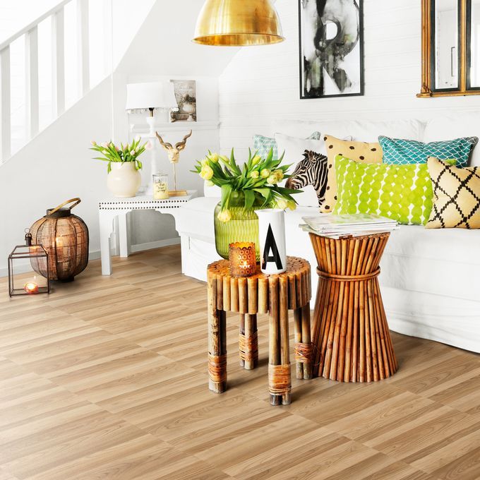 Ash wood effect flooring in a living room space with white sofa and bright accessories 