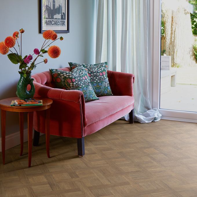 Basket weave style wood effect flooring laid in a front room with a pink couch