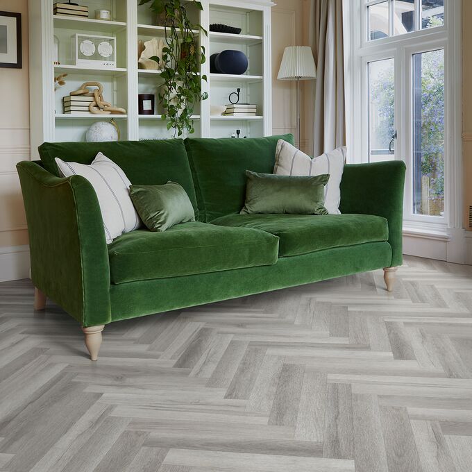 Grey coloured oak effect large parquet flooring with a green sofa