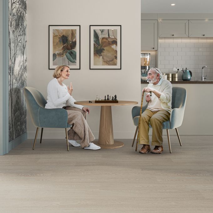 Oak effect flooring laid in a communal dining area with people enjoying a game of chess