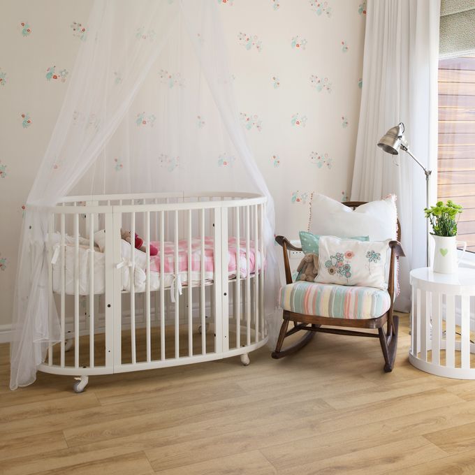 Light oak wood effect flooring in a nursery with white cot and rocking chair 