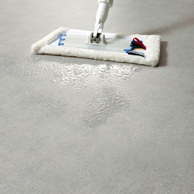 Light grey flooring being cleaning with a mop