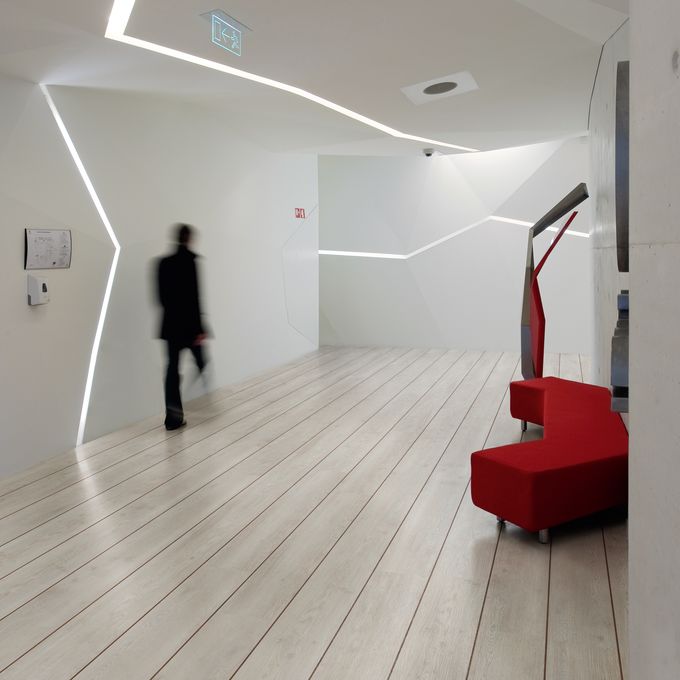 White oak wood effect flooring in a quirky corridor with red seat and strip lighting 