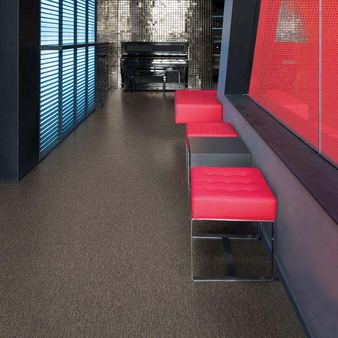 Dark stone effect flooring in a corridor with red and black seats