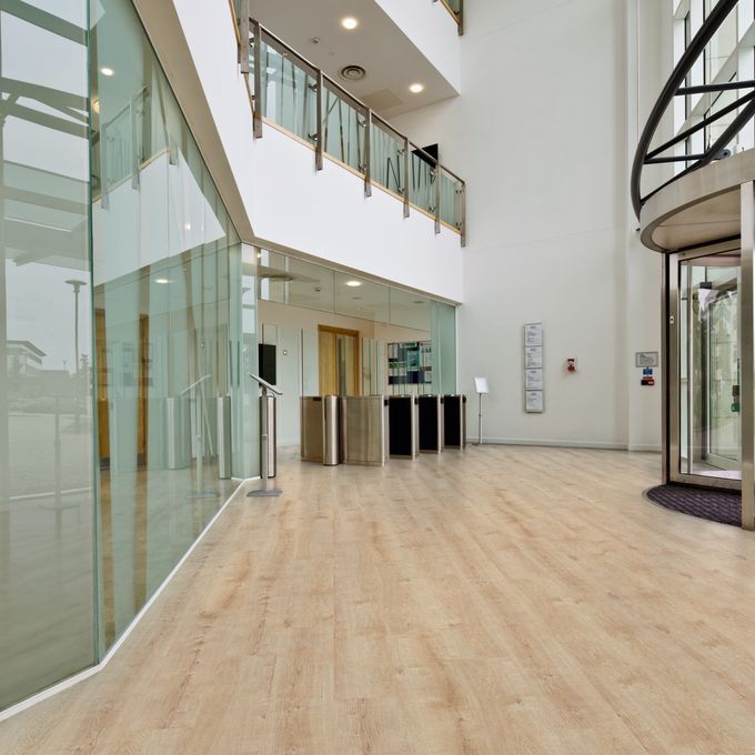 Large open space entrance with light wood effect flooring 