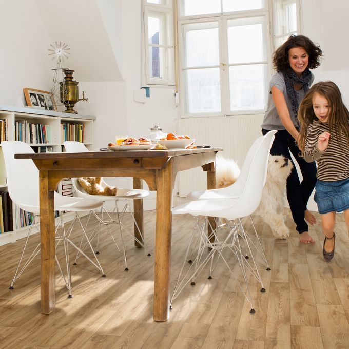 Light oak wood effect flooring in a family dining room with rustic table and white chairs