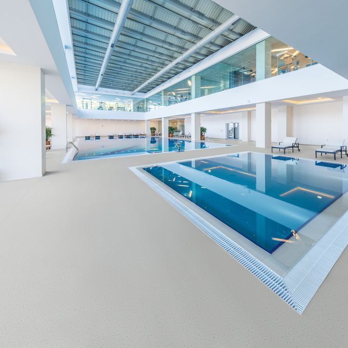 Neutral coloured safety flooring around a swimming pool area 